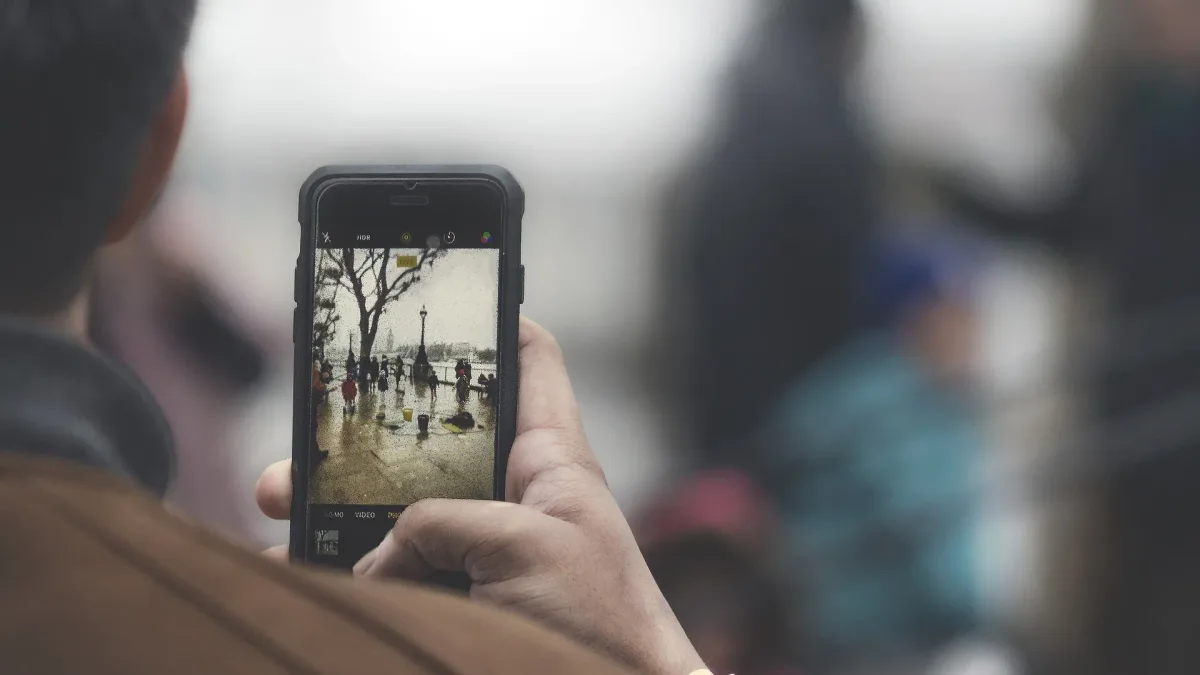 Person seen from behind taking a photo on a smartphone